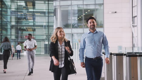 hombre de negocios y mujer de negocios caminando por el vestíbulo de una oficina moderna ocupada