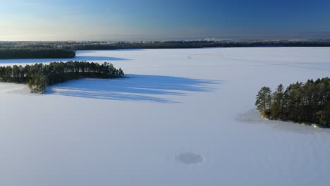 forward moving aerial over frozen lake with forest islands