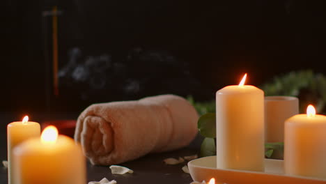 still life of lit candles with green plant incense stick and soft towels against dark background as part of relaxing spa day decor 4