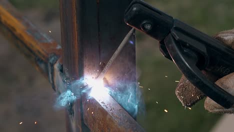 closeup craftsman fixes detail to fence pole using welding