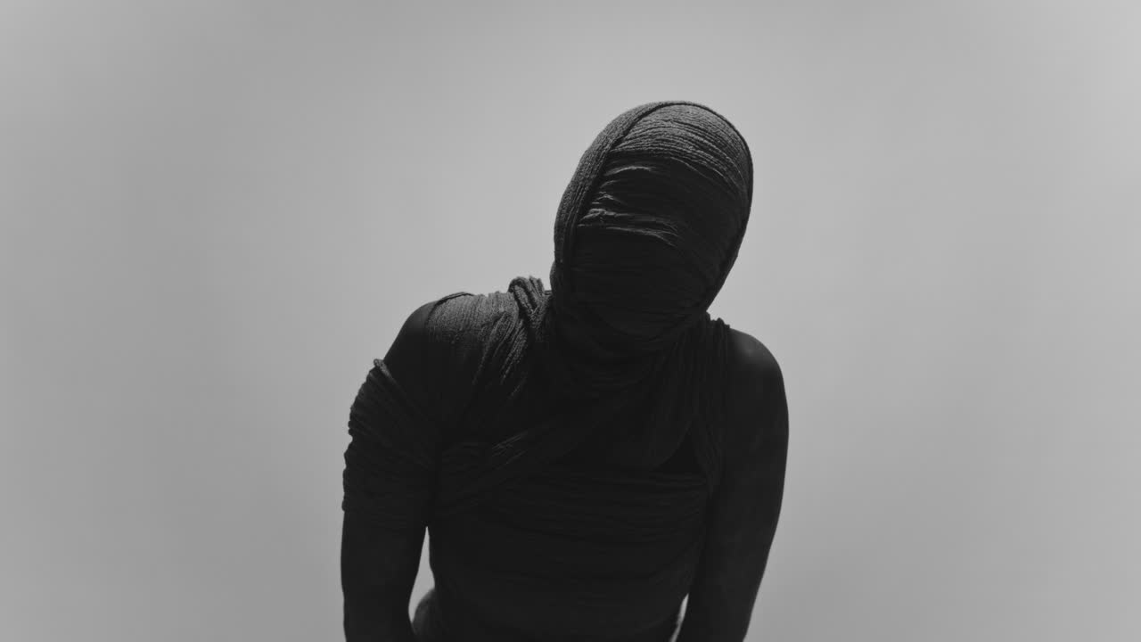 A mummy of a woman on a white backdrop moves her head