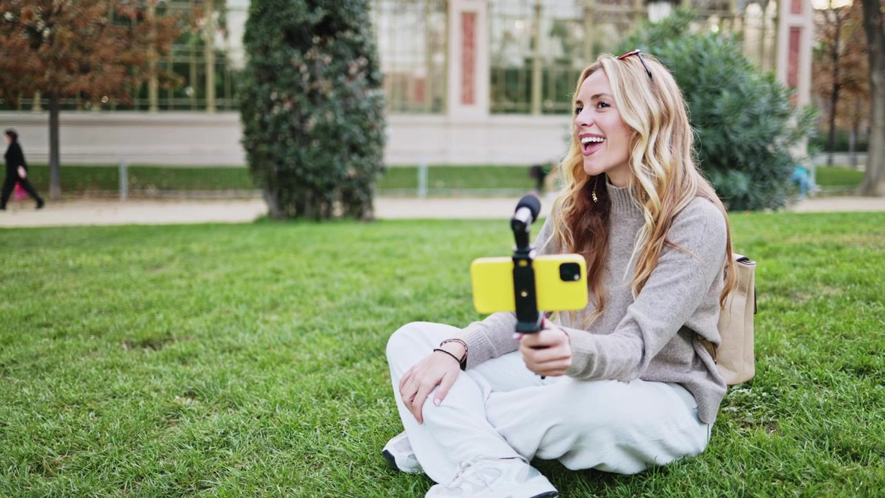 Donna felice che fa vlogging con lo smartphone in un parco