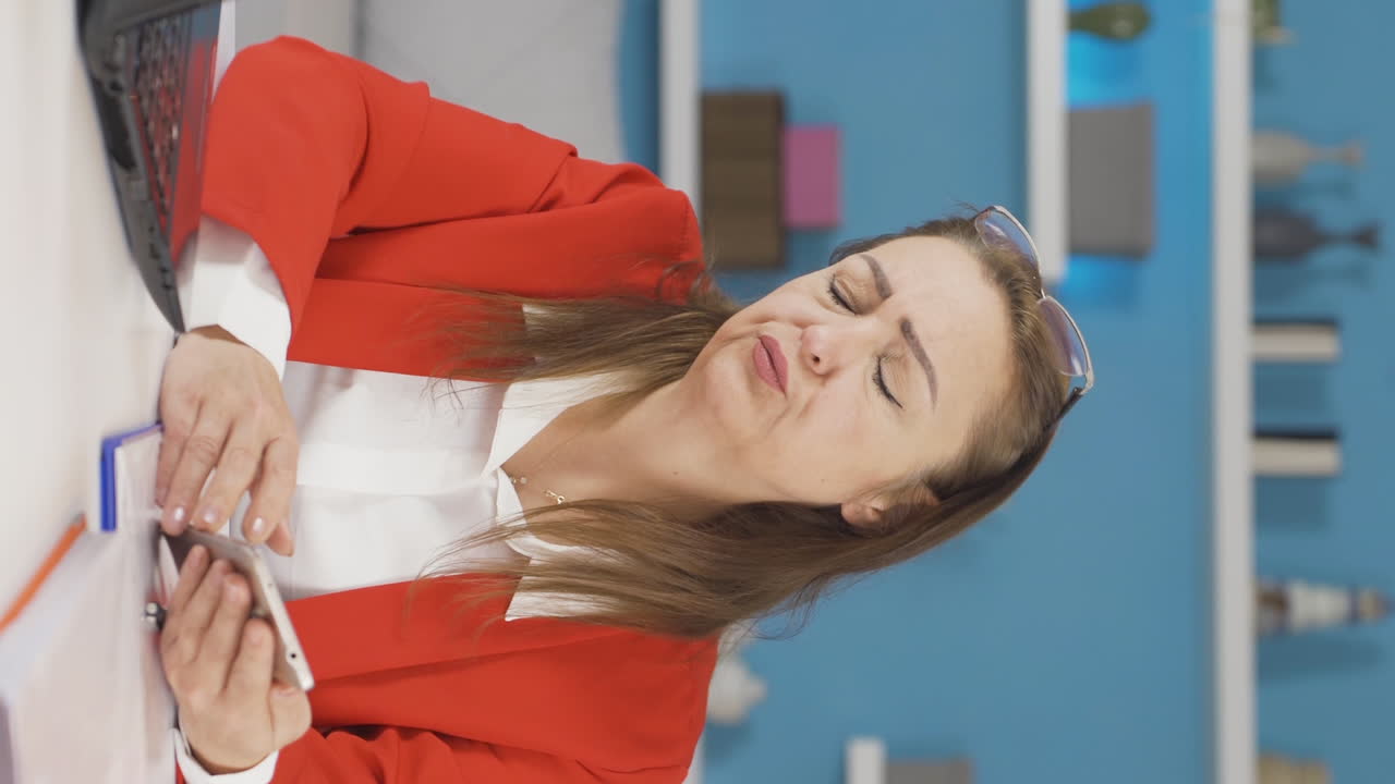 홈 오피스 직원 여성이 전화를 보면서 좌절하는 수직 비디오.