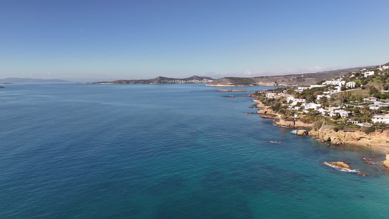 Riprese drone di una costa mediterranea con acque blu tranquille, litorale e un borgo marinaro.