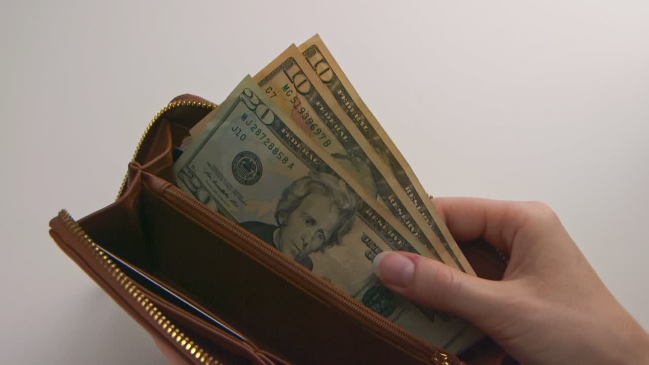 A caucasian woman's hands opening and showing a brown wallet containing $40 American Dollars