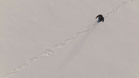 Man-walks-diagonally-across-a-field-covered-with-snow