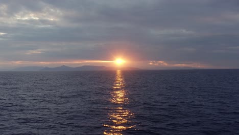 aéreo - volando hacia atrás sobre el mar al atardecer