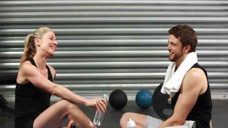 smiling fit couple sitting on mat talking