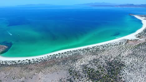vuelo descendente a una gran playa desértica frente al mar con botes turísticos en movimiento distante