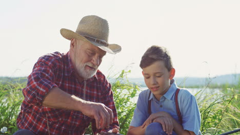 retrato de nieto con su abuelo sacando un pez de una caña después de atraparlo del lago