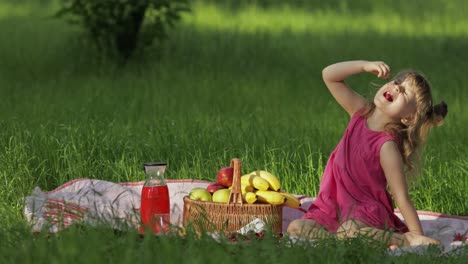 Weekend-at-picnic.-Lovely-caucasian-child-girl-on-green-grass-meadow-eating-merry,-cherry