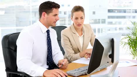 Business-team-looking-at-computer-screen-together-at-desk