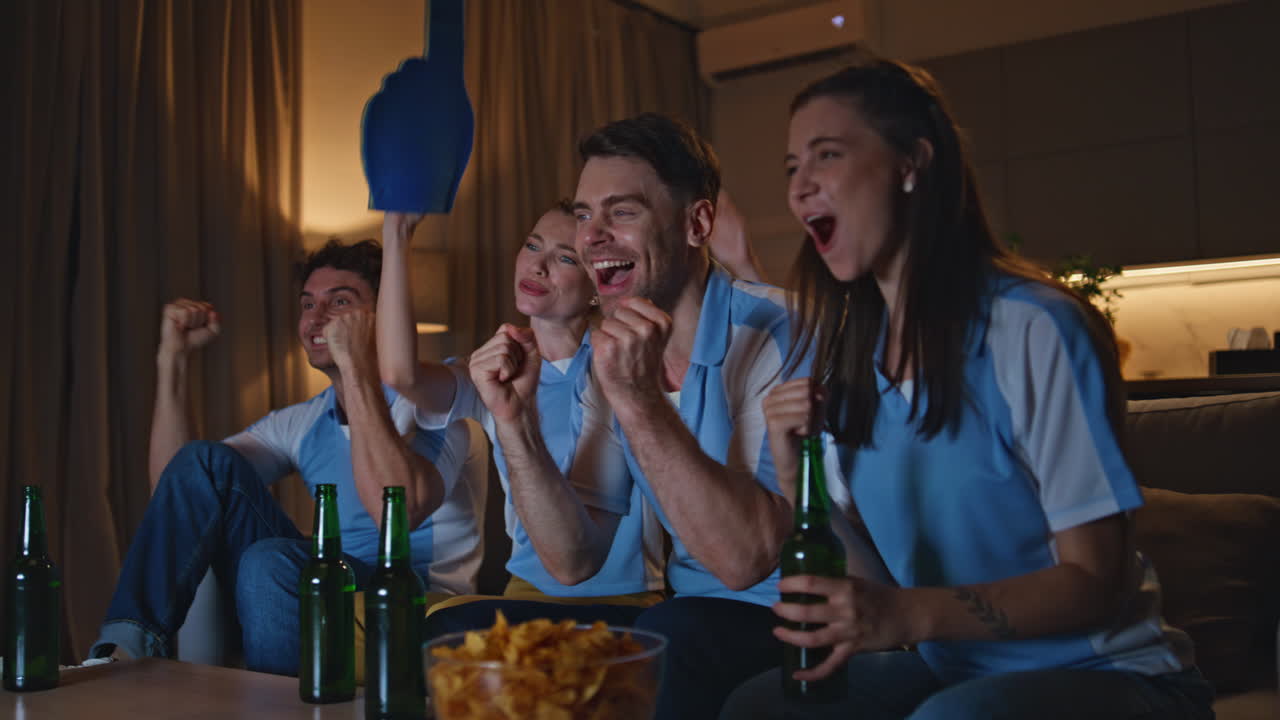 Sport fans watch tv football match on sofa cheering for favorite team close up.
