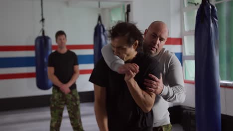 hombre caucásico aprendiendo autodefensa del entrenador en el gimnasio