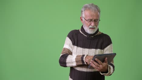 hombre barbudo y guapo con ropa cálida contra un fondo verde