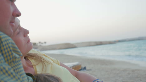 Relaxed-parents-and-child-with-cell-on-the-beach