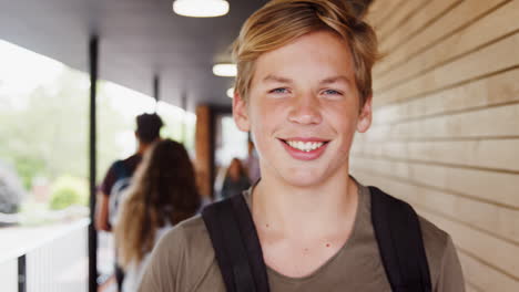 portrait of male student walking into focus outside building