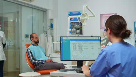 asistente haciendo citas mientras el médico de odontología está examinando al hombre