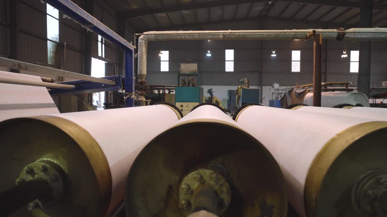 Rows Of Large Spinning Rollers With White Textile Fabric Inside Factory