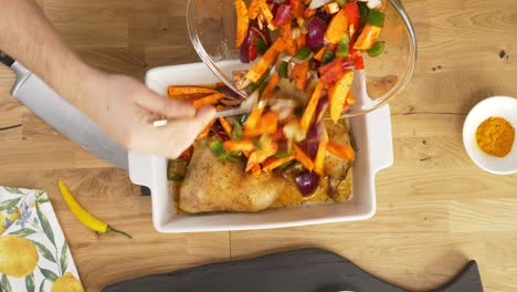 top view of a table top with a baking tray with a roasted chicken and sweet potatoes