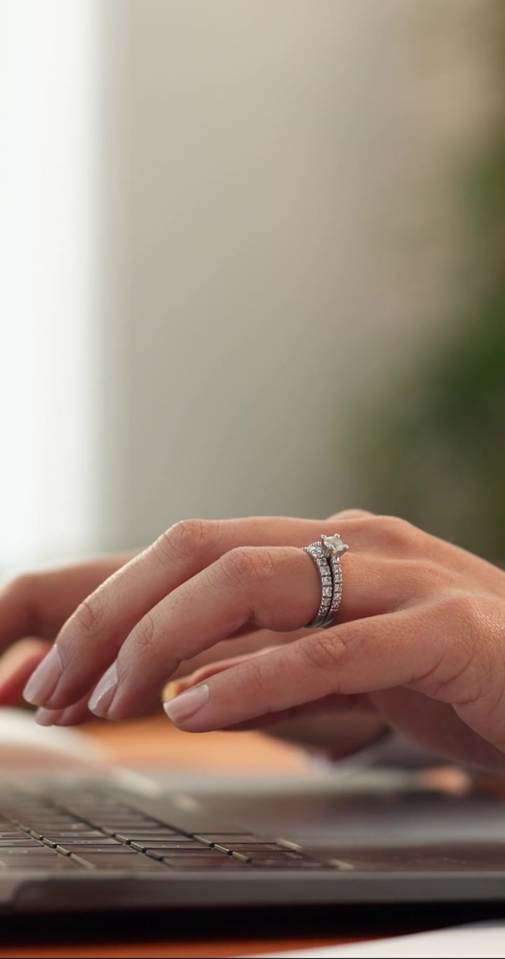 Primo piano di una donna con un anello di diamanti che digita sul laptop