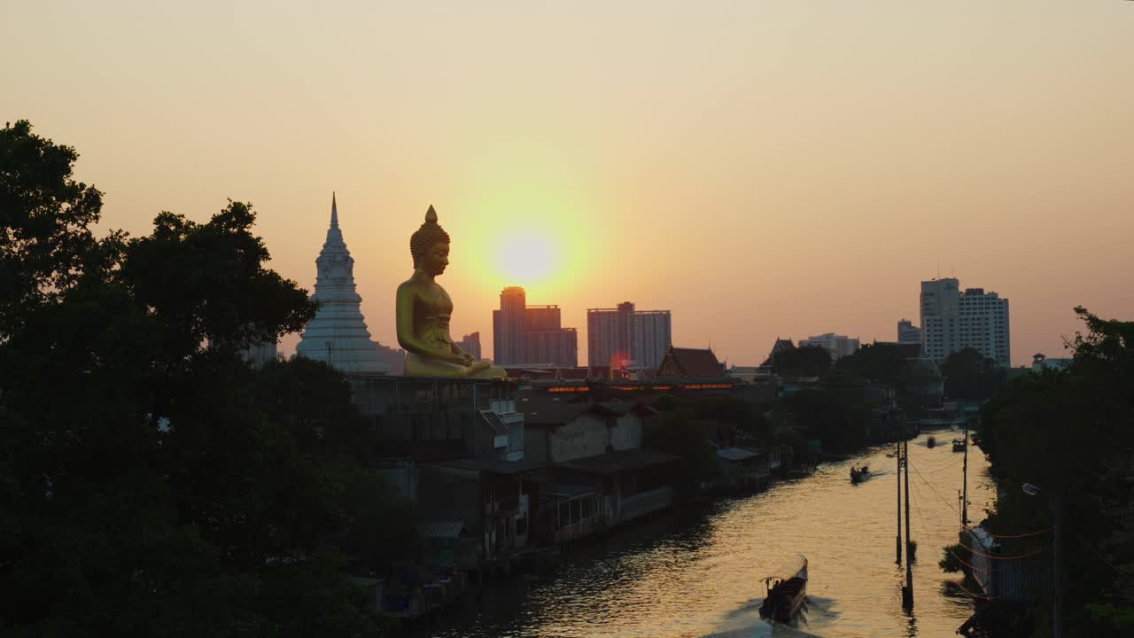 un canal en bangkok, tailandia, junto a la gran estatua dorada de buda al atardecer