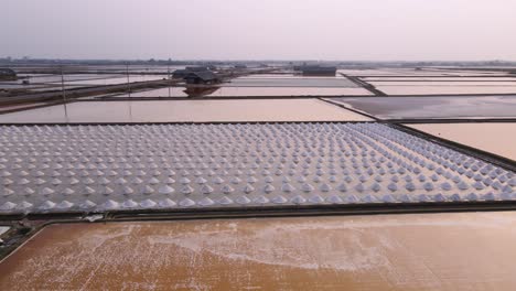 orbital drone shot of sea salt piles at a farm in thailand