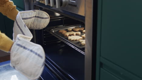 Midsection-of-biracial-woman-baking-christmas-cookies-in-kitchen-at-home,-in-slow-motion