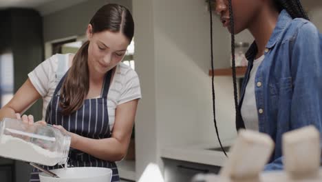 diversas amigas adolescentes felices con delantal cocinando en cámara lenta