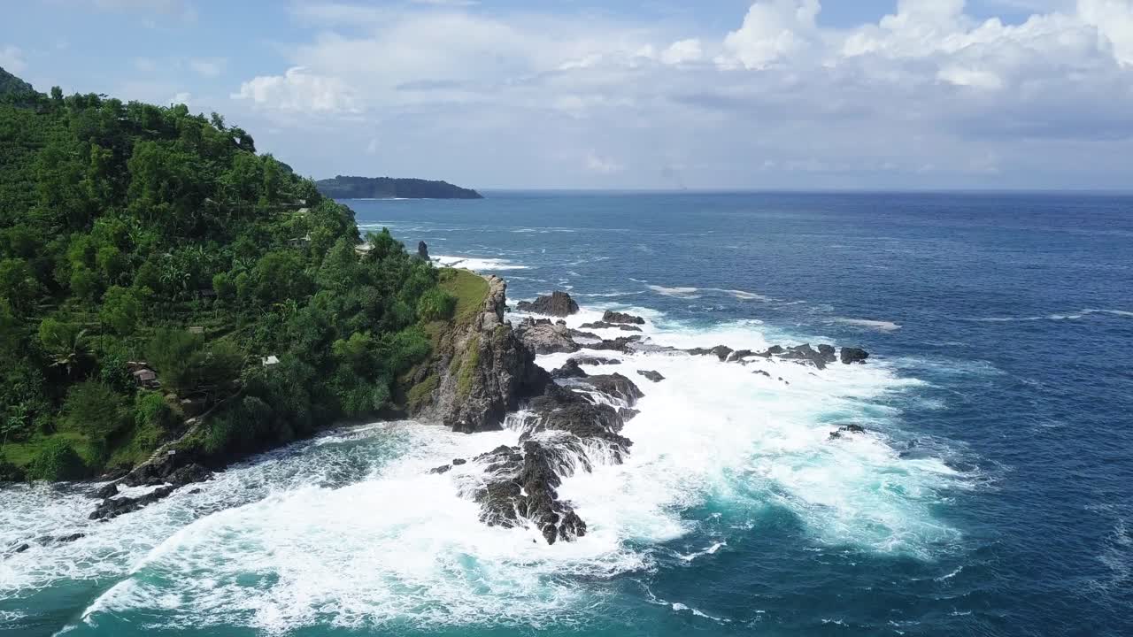 aerial view of the ocean waves foamingly hitting the rocks of a mountainous coast