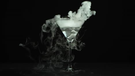 drink in glass of martinis with the effect of dry ice - drink in glass of martinis with the effect of dry ice on black background at studio. closeup
