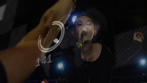 singer holding microphone wearing wristband on concert stage, showing circular graphic overlay