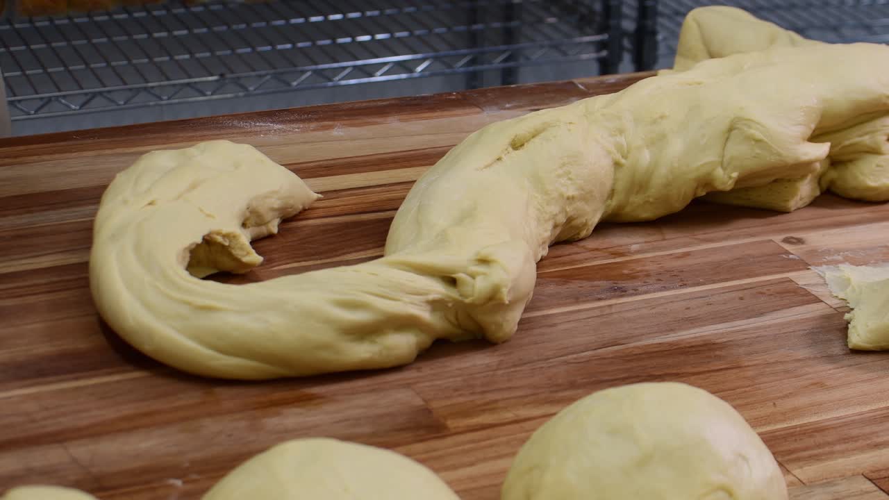 Close-up static shot of artisanal hands using bench scraper a metal tool to divide yellow dough in bakery environment