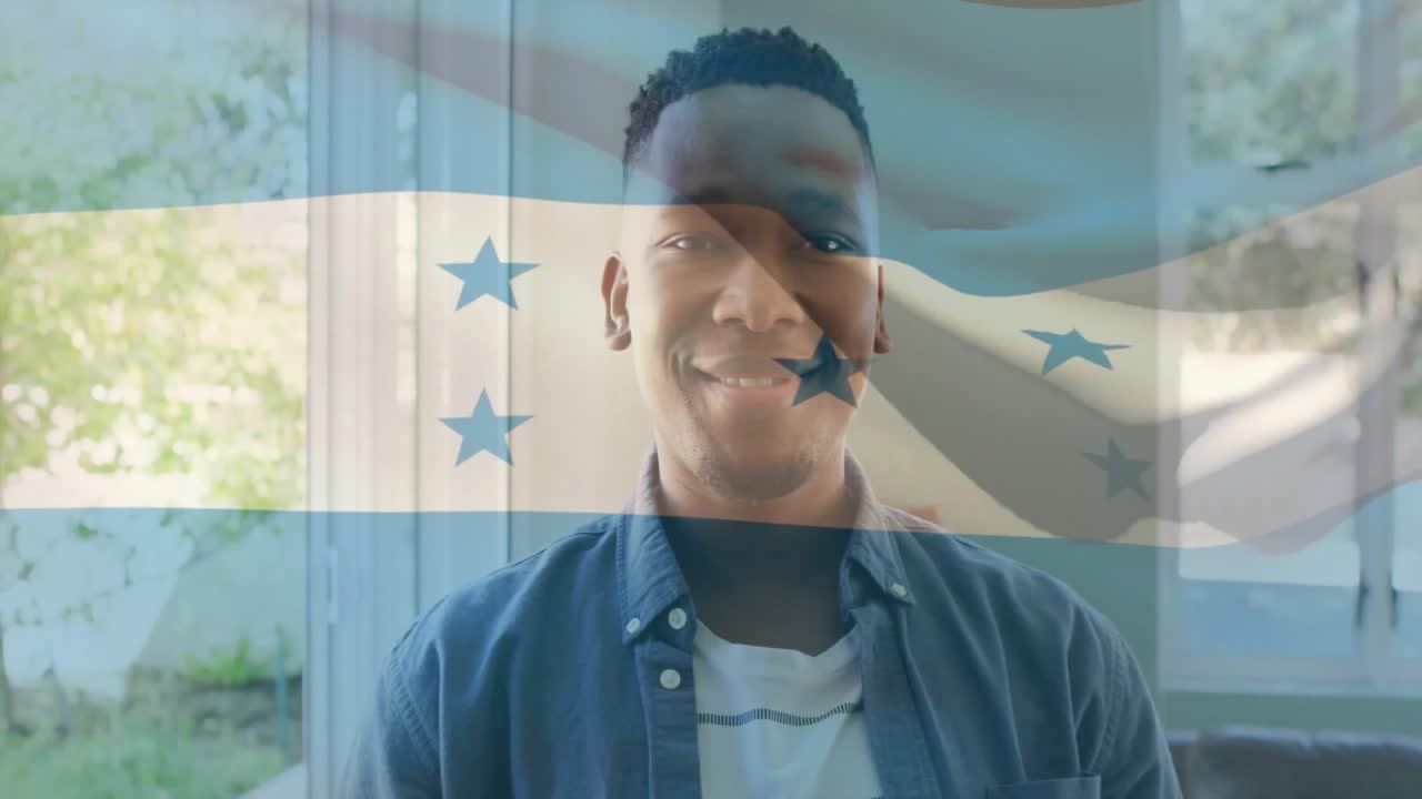 Hombre de pie en una sala de estar, mostrando un gráfico translúcido de la bandera de Honduras con una superposición tecnológica.