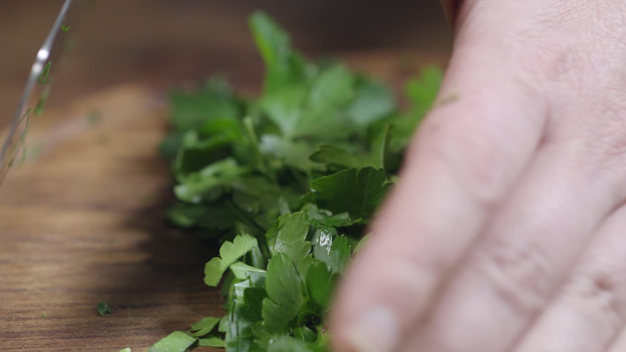 Proses memotong peterseli untuk saus chimichurri Argentina, koki menggunakan pisau kapak dapur