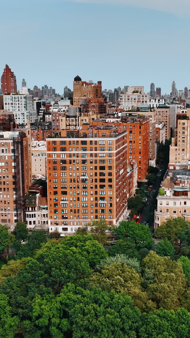 Orange block of flats in the residential area of New York. Drone footage distancing from the buildings above the green area. Vertical video