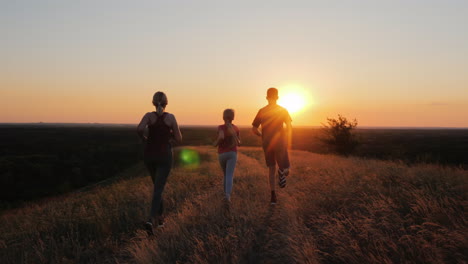 A-Young-Child-With-A-Couple-Jogging-Outdoors-In-Scenic-Location-On-The-Sunset