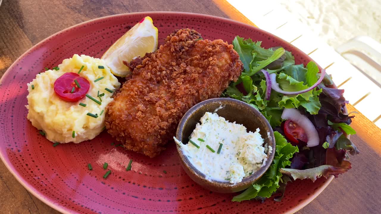 delicioso pescado frito con puré de patatas y ensalada en un plato rojo, mariscos, tiro de 4k