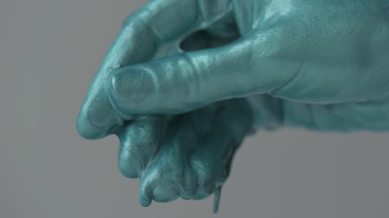 Two hands covered in bright blue paint are artistically intertwined, showcasing a creative moment in an art studio during the evening hours. This session emphasizes artistic expression and creativity