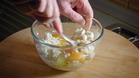 mixing oat flakes, eggs, and cottage cheese in a glass bowl using fork