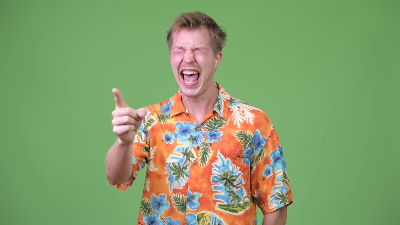 Young handsome tourist man laughing and pointing finger