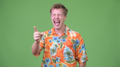 young handsome tourist man laughing and pointing finger