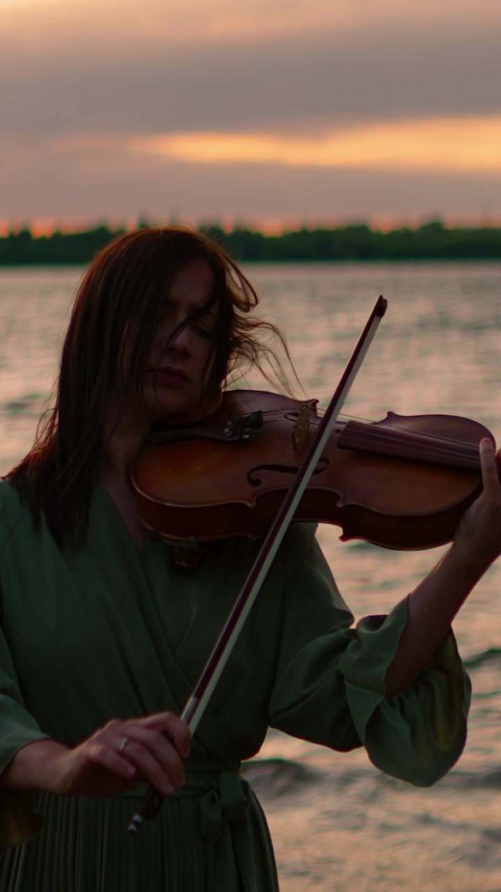Woman Playing Violin by the Lake at Sunset