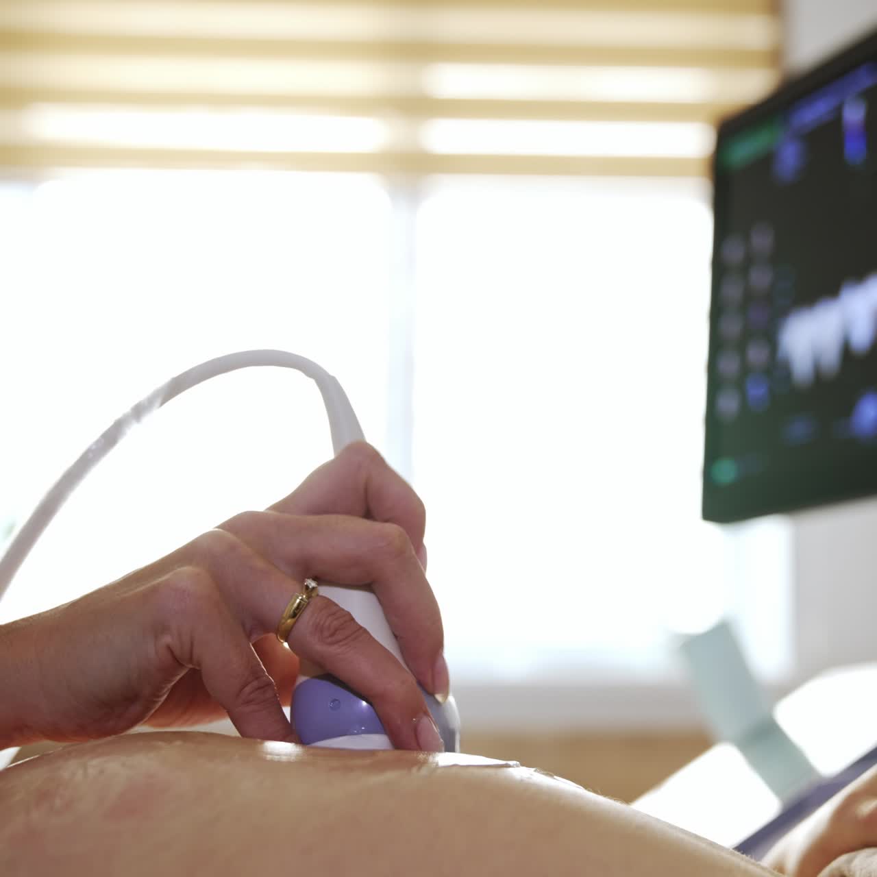 Physician carrying out the ultrasound examination for pregnant lady. Doctor is holding the transducer on the patient's lady and looking at the screen