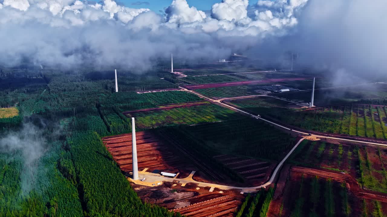 A green landscape where several wind turbine towers are under construction
