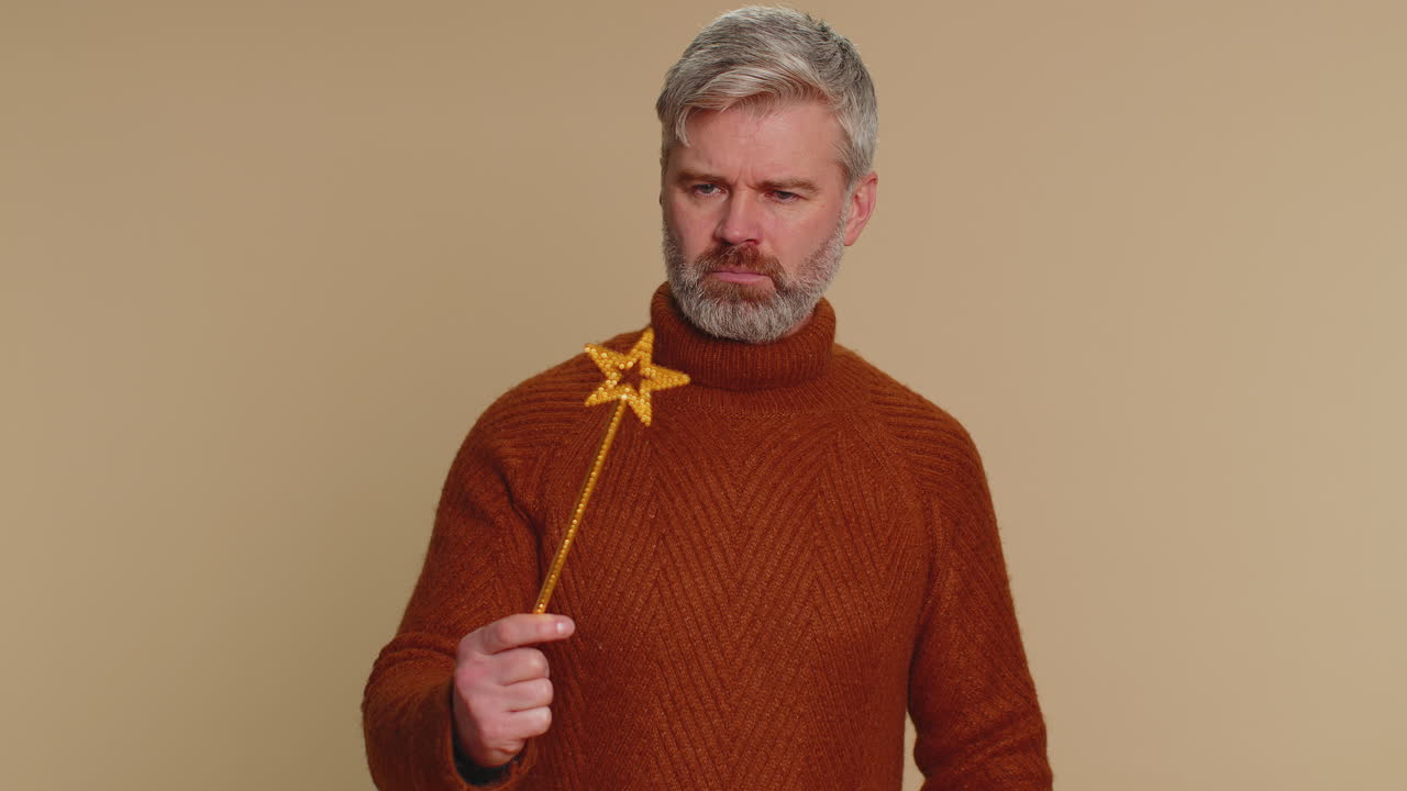 마법의 지이를 들고 갈색 스웨터를 입은 남자가 미소 짓고 웃는다