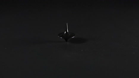 a spinning top rotating on a dark surface