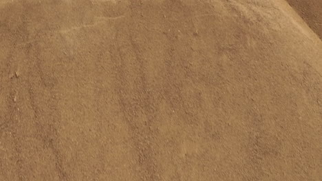 Close-up-aerial-view-of-a-green-mechanical-arm-moving-a-large-quantity-of-sand-in-an-excavation-site