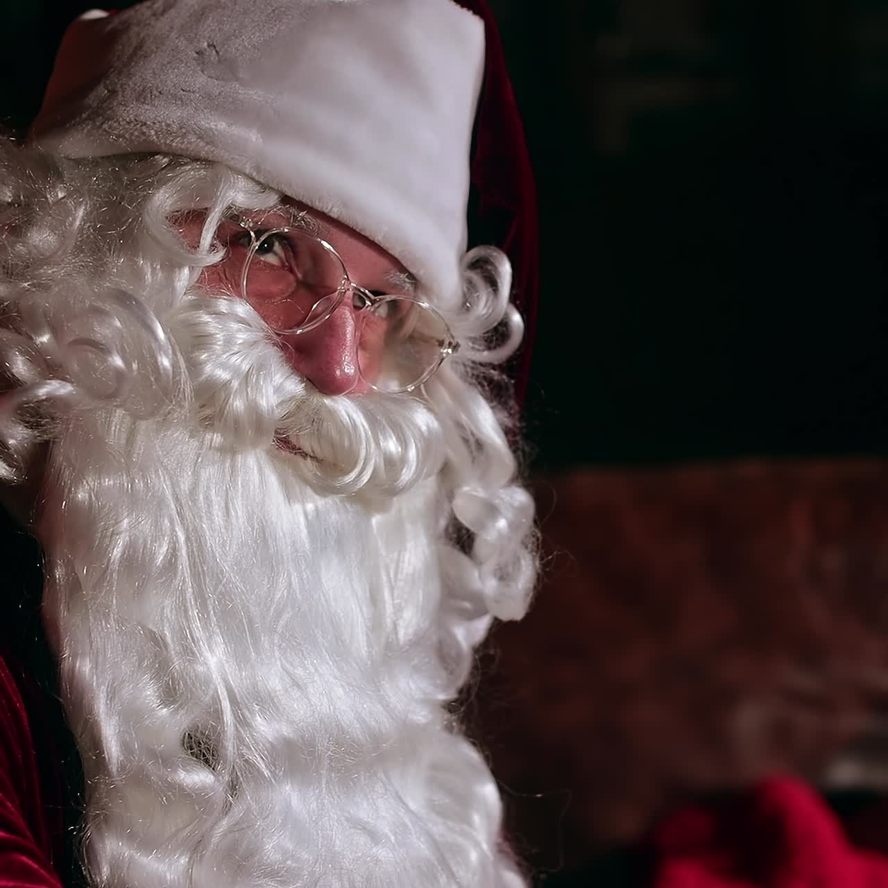 Babbo Natale seduto in casa. Famoso personaggio seduto di lato rispetto alla fotocamera che guarda lì per un po'. Concetto di celebrazione del Natale