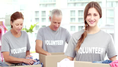 smiling friends volunteers separating clothes